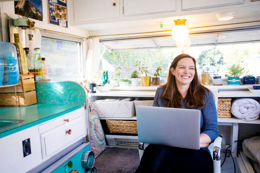 Woman smiling with her laptop sitting in an RV